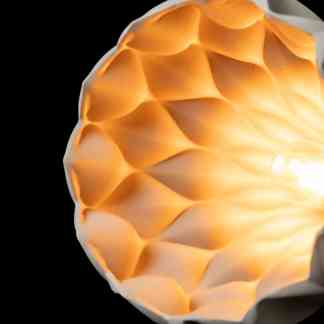 Vivid close-up of a 3D-printed geometric lampshade showcasing detailed design and warm glow.