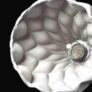 Close-up of a modern white 3D-printed lamp shade interior with intricate textured patterns against a black background.