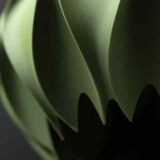 Close-up of a sleek green 3D-printed structure with smooth, textured surfaces, highlighting advanced manufacturing technology.