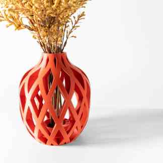 3D printed orange vase with lattice pattern and dried flowers on a white background.