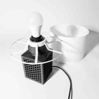 Minimalist black and white 3D printed light bulb with safety cage and white storage container.