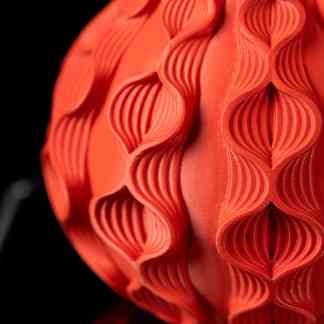 Close-up of intricate 3D printed geometric pattern on orange sphere for art and design models.