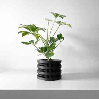 A black, sleek, 3D-printed plant holder with angular ridges holds a green indoor plant against a minimalist background.