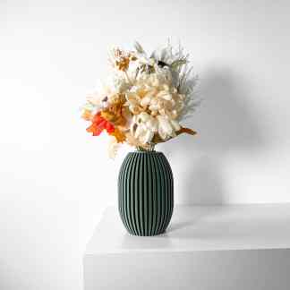 Beautiful artificial flower bouquet with autumn leaves in sleek vase on white surface.