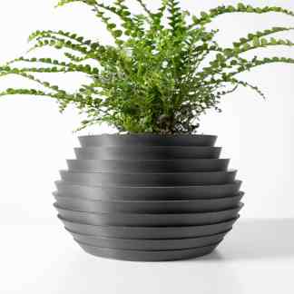 3D printed ceramic vase with layered design, holding a vibrant green fern plant for stylish home decor.