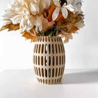 3D printed beige vase with cutout patterns, filled with artificial white and autumn-colored flowers.