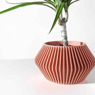Decorative pink ceramic vase with vertical ridges holding a green plant.