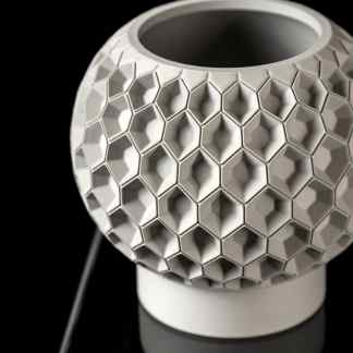 Sleek white 3D printed honeycomb pattern sculpture on black background, showcasing innovative design and engineering.