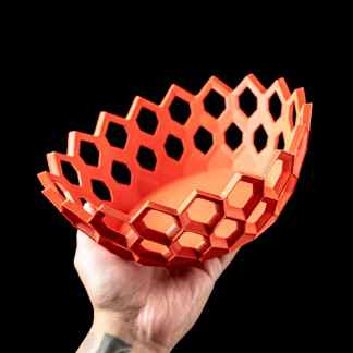 Bright orange 3D printed hexagon-patterned basket in hand.