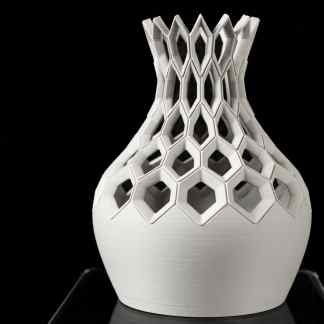 Close-up of a white, intricately designed 3D-printed vase with geometric openings, showcasing advanced additive manufacturing technology.