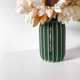 Stylish green vase with intricate geometric patterns holding white flowers, minimalistic decor for home or office.