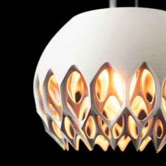 Close-up of a modern LED lamp with a geometric, perforated design, illuminated against a black background.