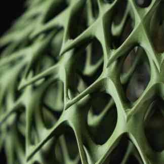 Close-up of a detailed 3D-printed green leaf with intricate geometric patterns showcasing advanced additive manufacturing techniques.