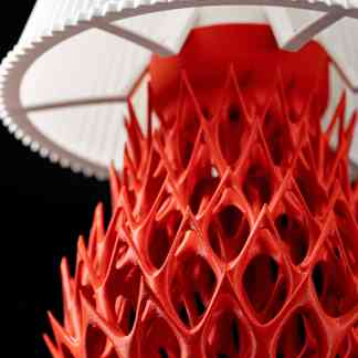 Close-up of 3D printed lattice structure with detailed design and vibrant red color.