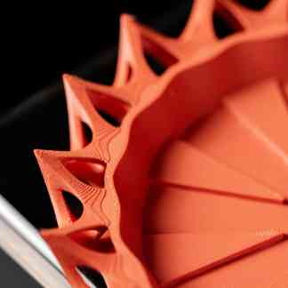 Detailed 3D printed gear showcasing complex lattice structures in vibrant orange, emphasizing custom engineering and 3D printing technology.