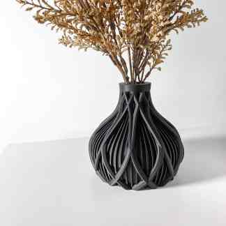 Modern 3D printed black vase with intricate openwork patterns, displaying dried flowers.