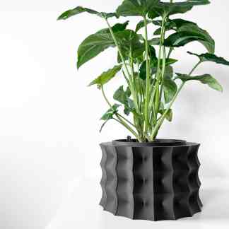 A 3D-printed black geometric planter with a vibrant green plant, exemplifying advanced 3D printing technology and creative home decor.