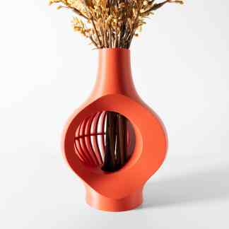 Stylish orange vase with unique geometric cutouts holding dried floral arrangement for home decoration.