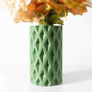 Detail of a green 3D-printed vase with a geometric diamond pattern, holding a floral arrangement.