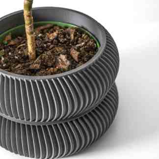 Stylish black ribbed plant pot with soil and young plant stem for modern home decor.