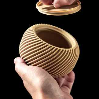 Close-up of a beige 3D printed vase with ribbed texture, held by hands against black background.