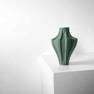 Stylish green geometric ceramic vase displayed on a white pedestal in a minimalist setting.