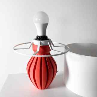 Modern geometric lightbulb sculpture with red and white elements, innovative 3D printed art piece.