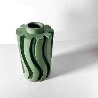 Close-up of a green 3D-printed mechanical component with intricate wave-like details.