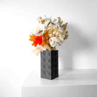 Vase with 3D printed geometric design holding artificial flowers and autumn leaves.