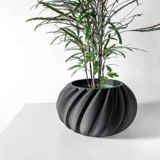 3D printed black ribbed vase with lush green plant for modern interior decoration.