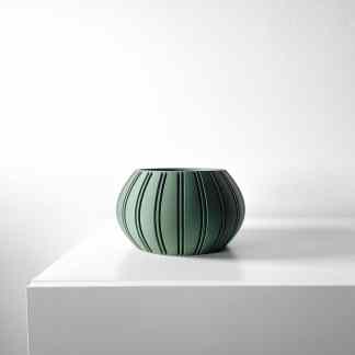 Elegant modern green vase with black lines on a white surface.