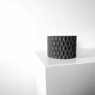 3D printed black geometric sculpture on white display table.