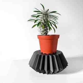 3D printed black geometrical plant stand with terracotta pot on white background.