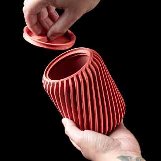 Detailed view of a 3D printed red lamp shade with intricate vertical ridges on a black background.