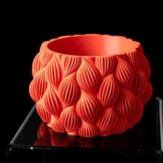 3D printed decorative orange vase with textured petal pattern on black display stand.