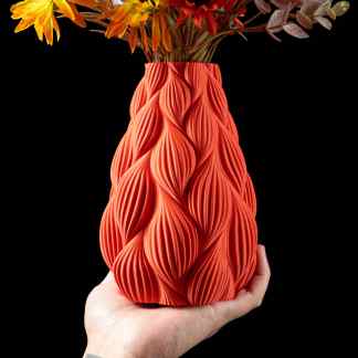 Hand holding a vibrant, uniquely textured 3D-printed vase with flowers.
