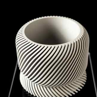 3D printed white decorative bowl with intricate ridged design on black background.