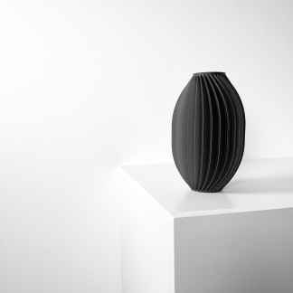 Sleek black 3D printed vase with ribbed design displayed on white shelf for stylish home decor.