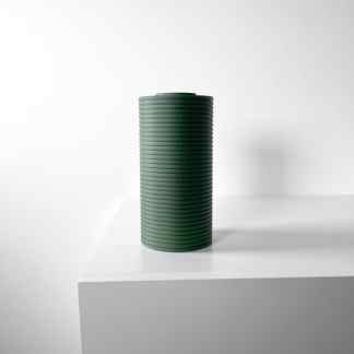 Minimalist green textured vase on white pedestal against white background.