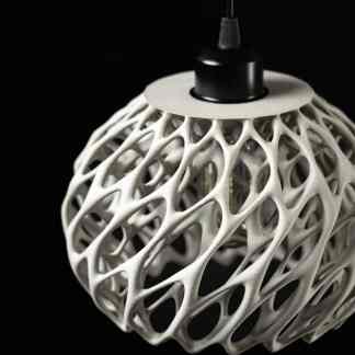 Intricate white 3D printed lampshade on a black background, showcasing modern 3D printing technology.