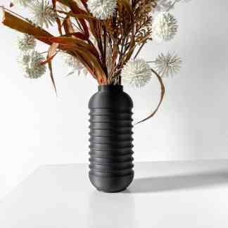 Elegant black ceramic vase with textured ridges, displaying dried white flowers and foliage.