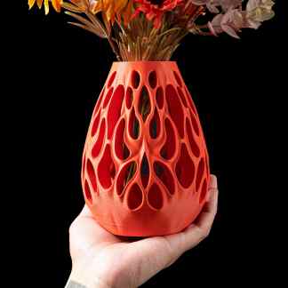 Vibrant orange 3D printed vase with intricate, organic cutout design, perfect for modern interior decor.