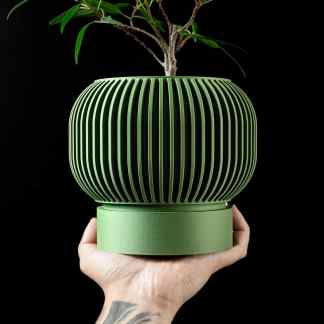Stylish green ceramic planter with vertical slats and a small tree, perfect for modern interior design.