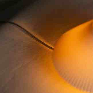 Close-up of modern, textured 3D lamp surface in warm lighting.